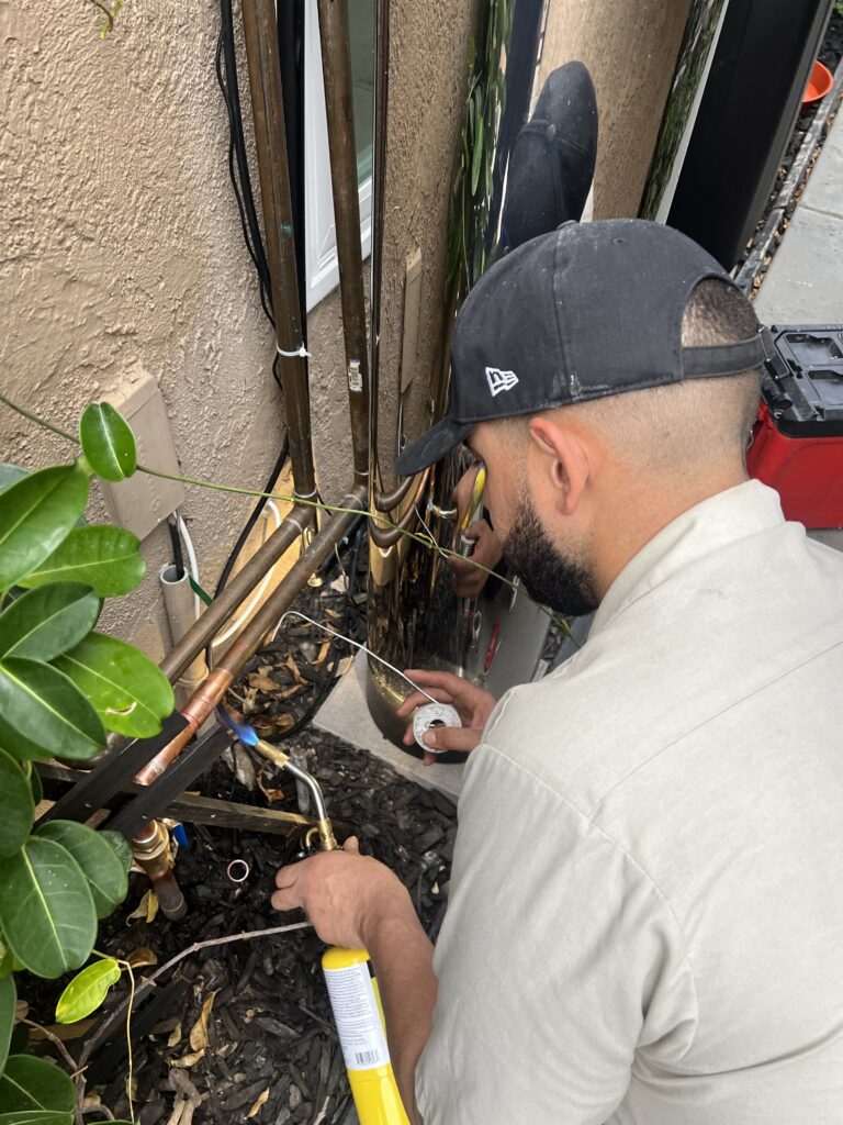 Lay It Rite Plumbing technician soldering a copper water line outside an Orange County home