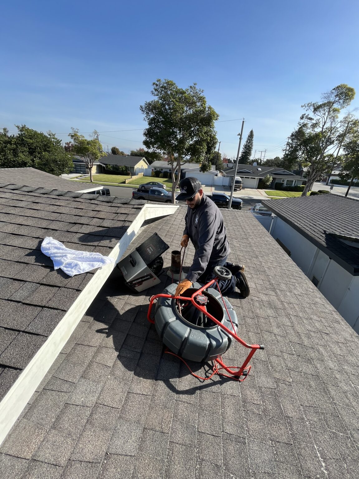Andy, owner of Lay It Rite Plumbing, clearing a drain line from a home's roof in Orange County