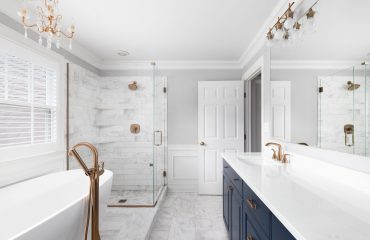 A beautiful bathroom with a blue vanity cabinet, standalone bath